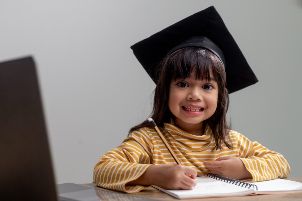Happy Asian school kid graduate in graduation cap